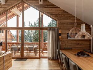 Wooden chalet interior with large glass doors and dining table
