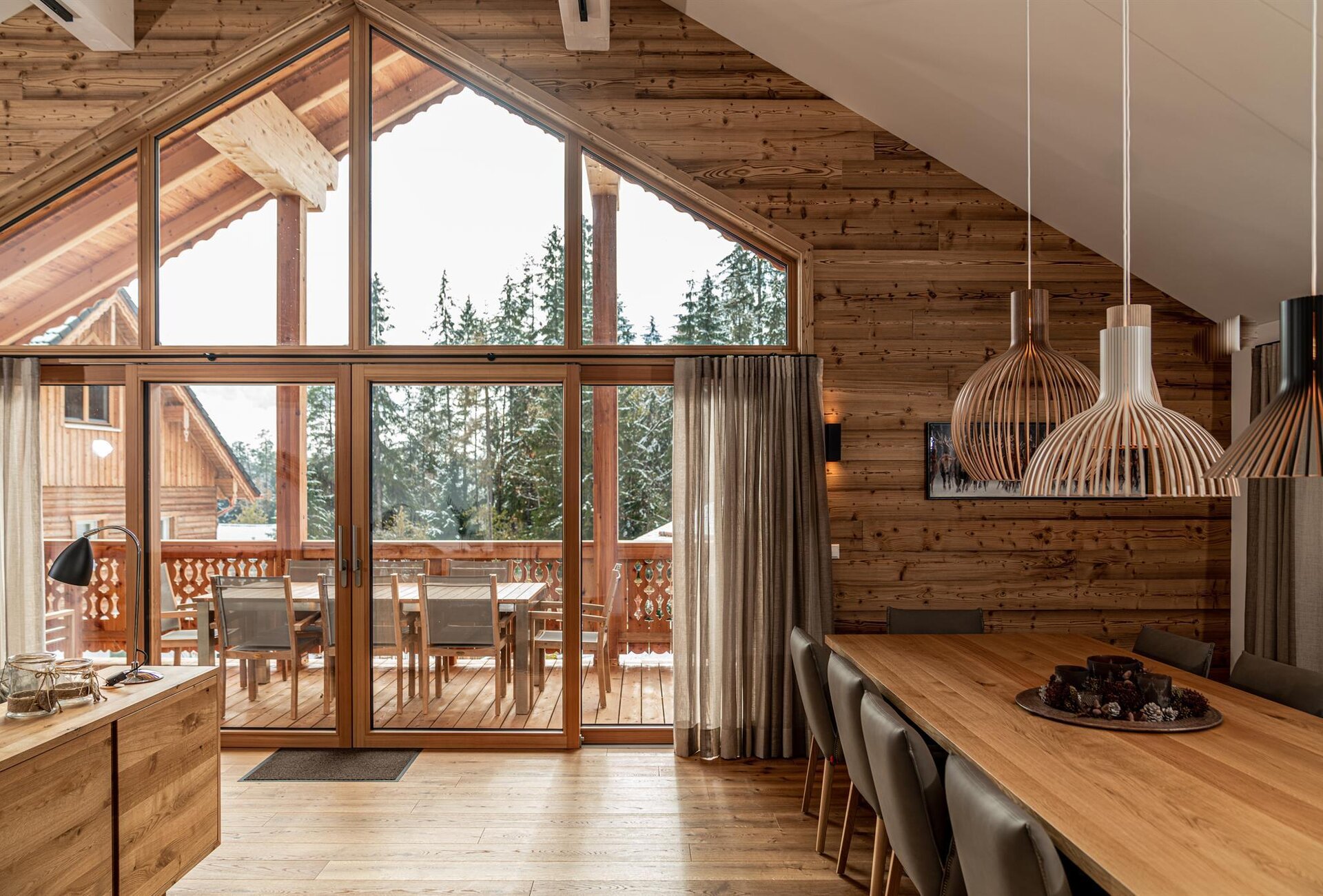 Wooden chalet interior with large glass doors and dining table