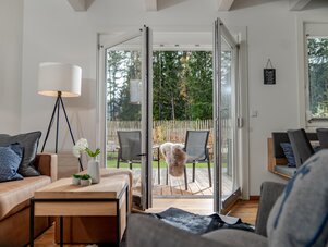 Wohnzimmer mit offenen Glastüren zur Terrasse und Stühlen