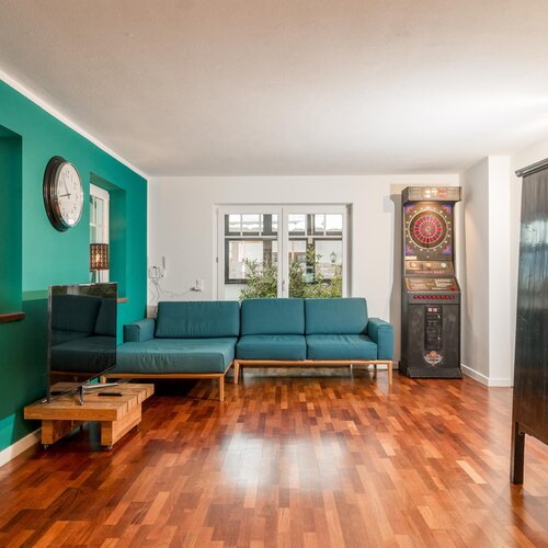 Living room with teal accent wall and teal sofa, dart arcade machine
