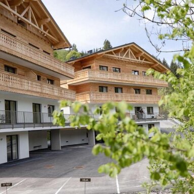 Chaletartiges Holzwohngebäude mit mehreren Balkonen im Bild