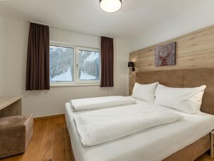 Doppelbett in modernem Hotelzimmer mit Holzverkleidung