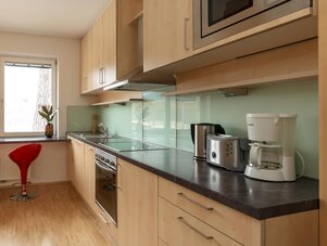 Modern kitchen with light wood cabinets, glass backsplash, and appliances