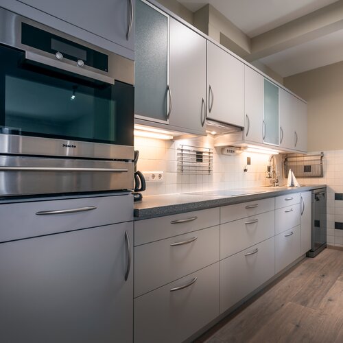 Modern kitchen with built-in stainless steel oven and gray cabinets | © Tieber Michael