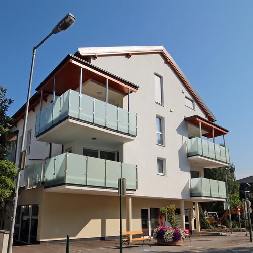 Modern white apartment building with glass balconies on a sunny street