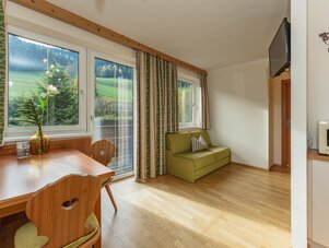 Heller Wohnbereich mit grünem Sofa und großen Fenstern