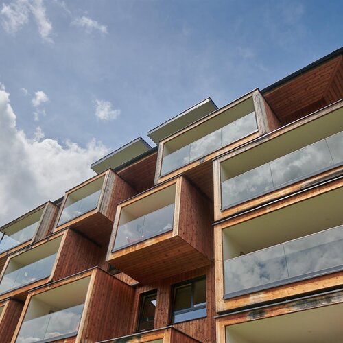 Low-angle view of a multi-story wooden building with glass balconies