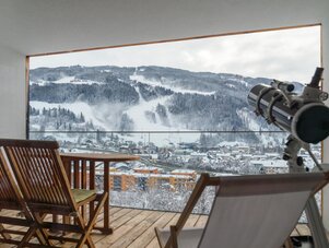 Snowy mountain village seen from balcony with telescope