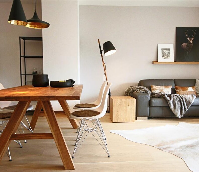 Helles modernes Wohnzimmer mit Esstisch aus Holz und grauem Sofa