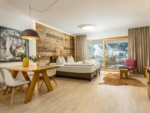 Hotel room with wooden feature wall, bed, dining table, and balcony doors
