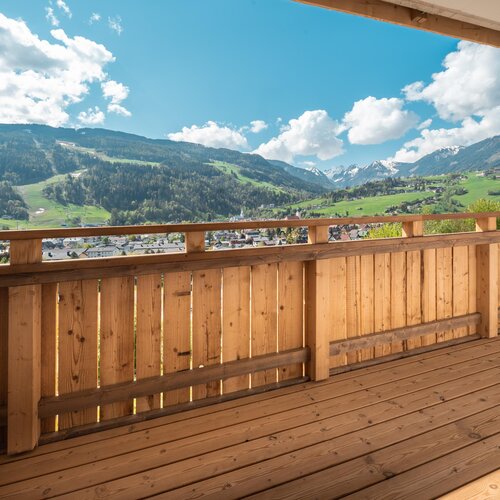 Holzbalkon mit Blick auf grüne Täler und Berge
