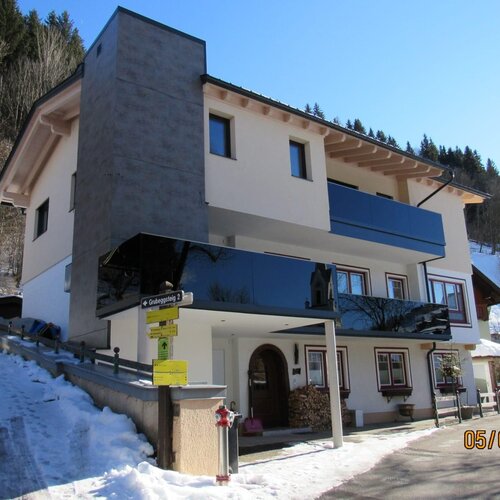 Modernes weißes Haus in verschneiter Hanglage mit Glasbalkon