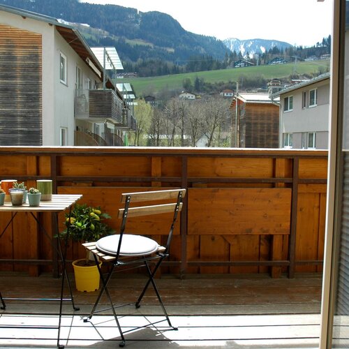 Balcony with wooden railing, table with potted plants, and mountain view.