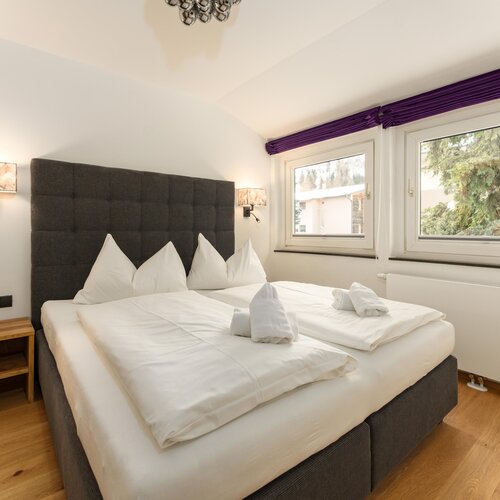 Large double bed with white linens and tufted headboard