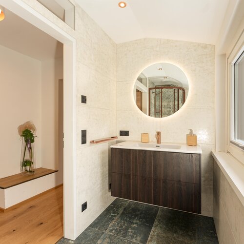 Modern bathroom with round backlit mirror and dark wood vanity