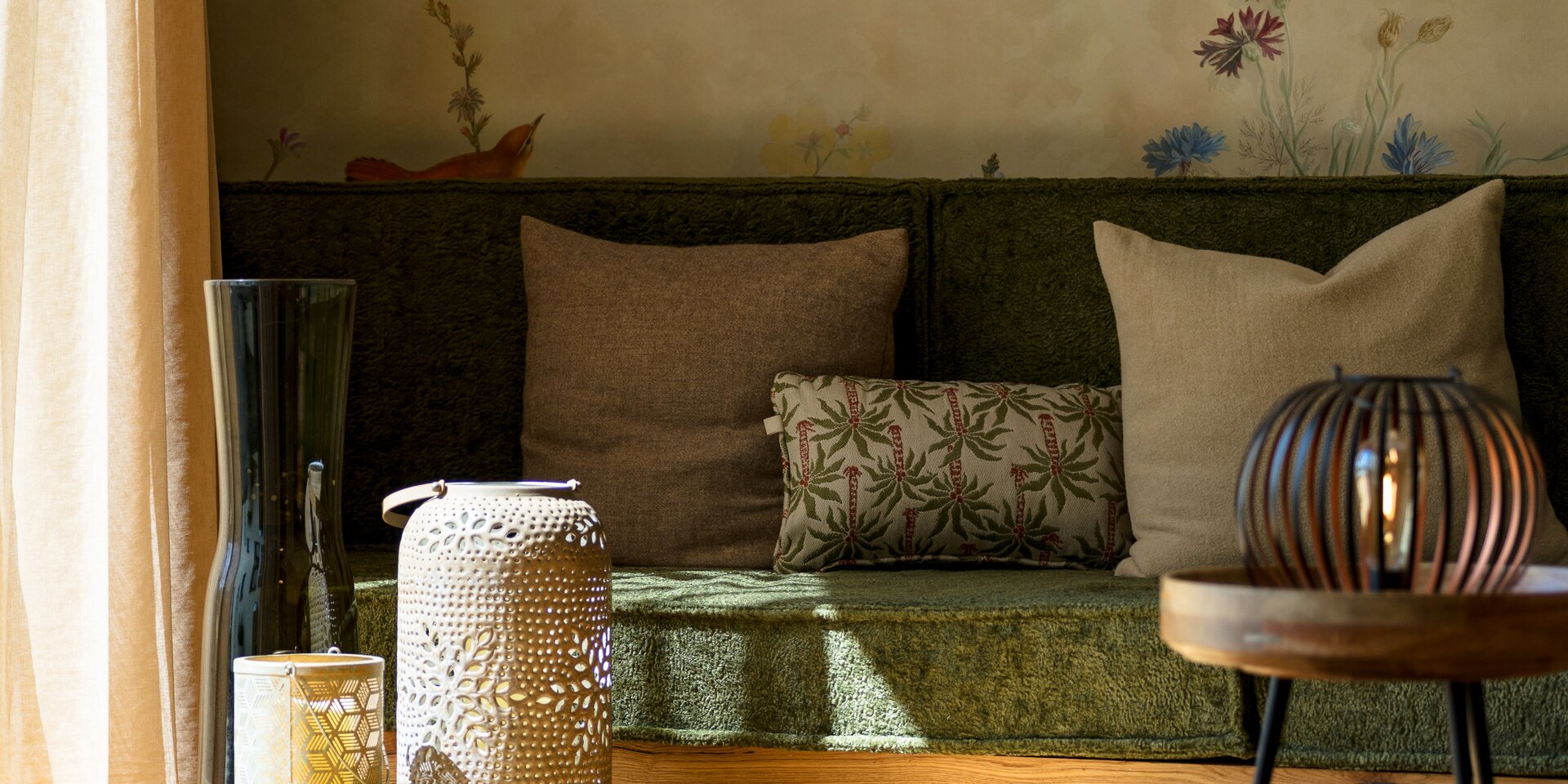 Sonnendurchflutetes Wohnzimmer mit grünem Sofa und Laternen