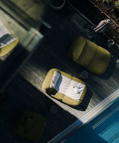 Luftaufnahme einer Poolterrasse mit grünen Loungesesseln und Magazinen