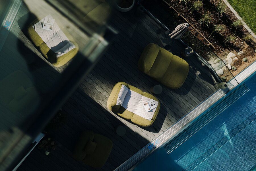 Luftaufnahme einer Poolterrasse mit grünen Loungesesseln und Magazinen