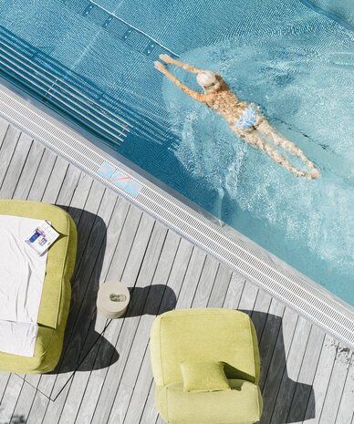 Aerial view of a poolside deck with green loungers