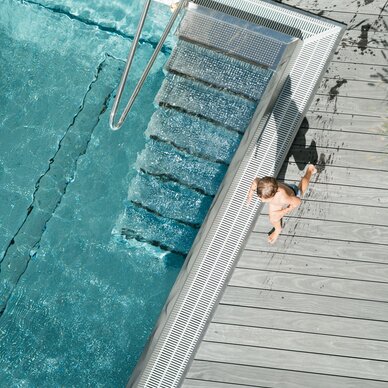 Top-down view of pool with metal ladder and child