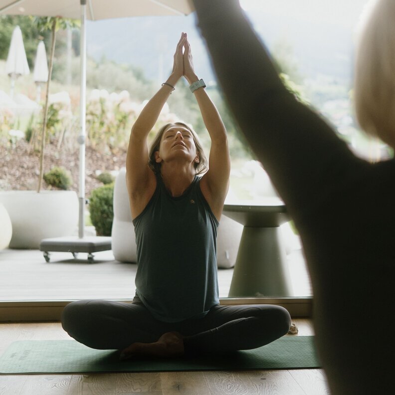 Woman practicing seated yoga indoors with hands raised
