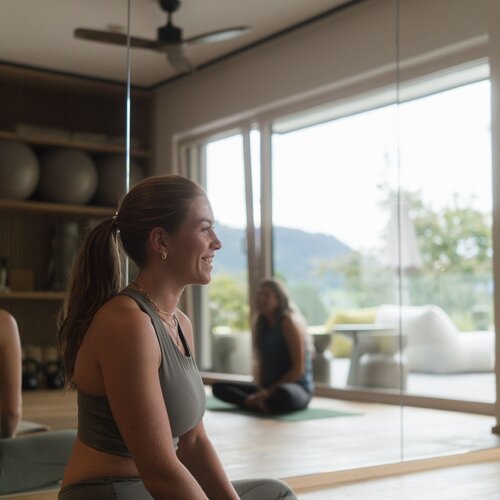 Woman practicing yoga in a sunlit studio with mirrors