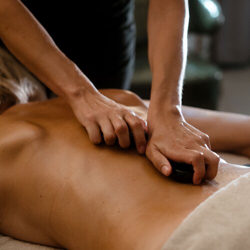 Massagetherapeut führt Hot-Stone-Massage am Rücken durch